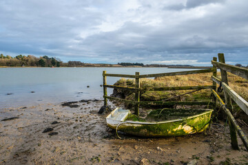 Old battered rowing boat on the shore of the River Deben in Woodbridge