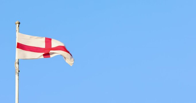 Footage of the Saint George flag blowing in the wind on a sunny summers day showing the blue sky in the background