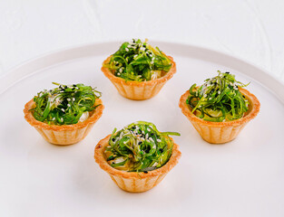 Gourmet seaweed salad tartlets on white plate