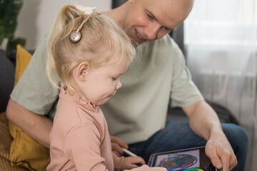 Close-up Deaf child girl with cochlear implant studying to hear sounds and have fun with father -...