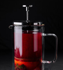Fruit infused tea in french press on dark background