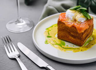 Gourmet salmon brioche with poached egg and basil