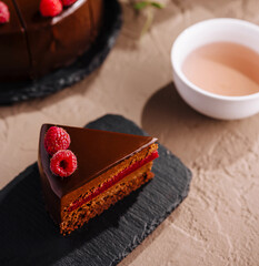 Elegant raspberry chocolate cake slice with tea setup