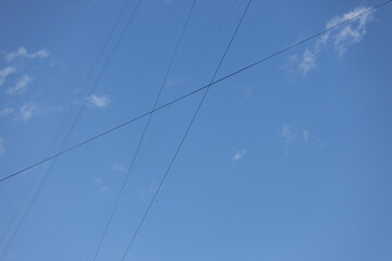 Electrical wires between buildings against a background of blue sky with clouds