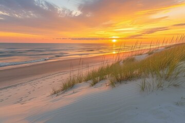beach sunset over calm sea with footprints in sand dunes