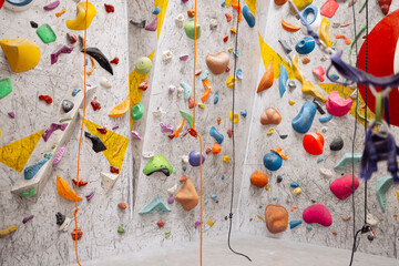 Interior shot of indoor climbing centre without people with assortment of colorful and challenging climbing walls. White wall with climbing holds in gym.