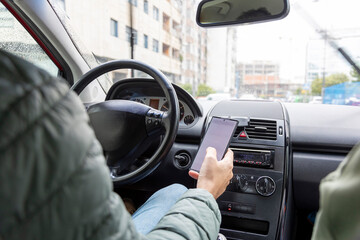 A male driver in a green jacket is dangerously using a smartphone while driving, showing modern...