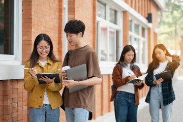 Asian students joining study book, smiling with laptop computer tablet at high school university,...