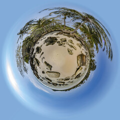 Little planet spherical panorama of sandy beach with boulders with palm trees tropical island in sea with blue sky.