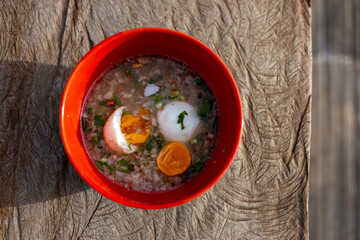 Selective focus Thai style minced pork porridge with boiled egg. Breakfast in an orange cup Helps increase energy