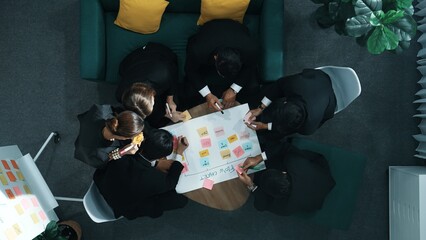 Close up of professional business team hands writing and putting sticky note on scrum task board....