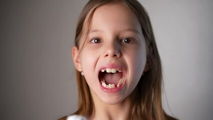 Portrait of a girl pulling out her baby tooth, close-up.