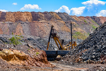 Heavy excavator loading ore to the railway carriage in iron ore quarry