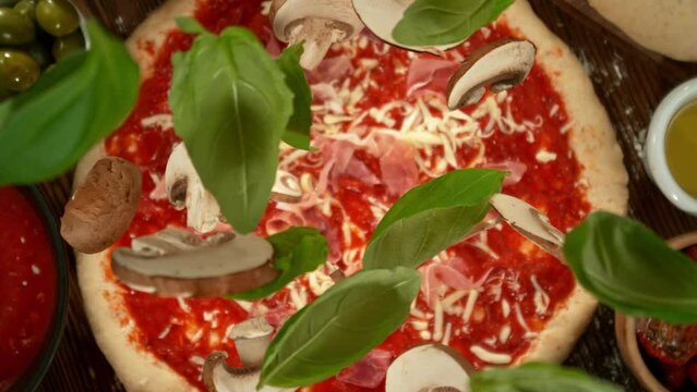 Super slow motion of falling basil leaves and mushrooms on pizza dough with camera follow and rotation. Filmed on high speed cinema camera, 1000 fps.