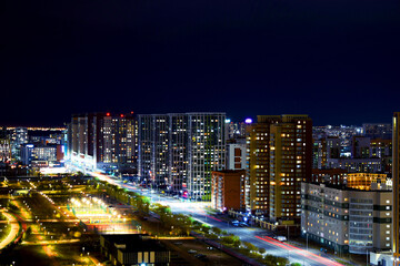 Obraz premium The center of the night city of Astana, illuminated by the light of houses, lanterns and car headlights. Kazakhstan, Asia. High-rise buildings.