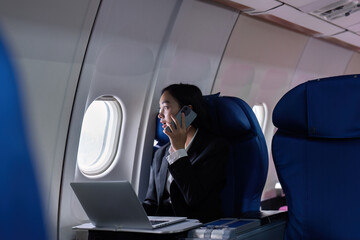 Beautiful Asian businesswoman working with laptop and mobile in aeroplane. working, travel,...