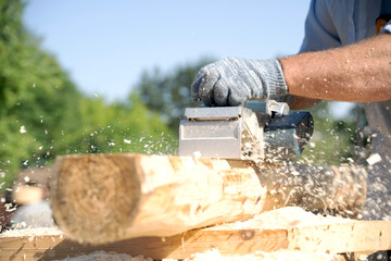 a carpenter works with an electric pipe on a sunny day