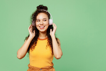 Young woman of African American ethnicity wears yellow tank shirt top listen to music in headphones...