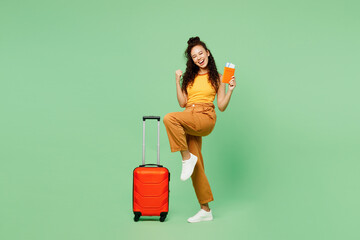 Traveler woman wear yellow casual clothes hold bag passport ticket do winner gesture isolated on...