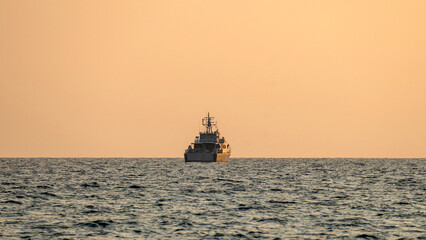 Warship at sea on duty at sunset