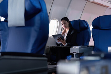 businesswoman flying and working in an airplane in first class, businesswoman sitting inside an...