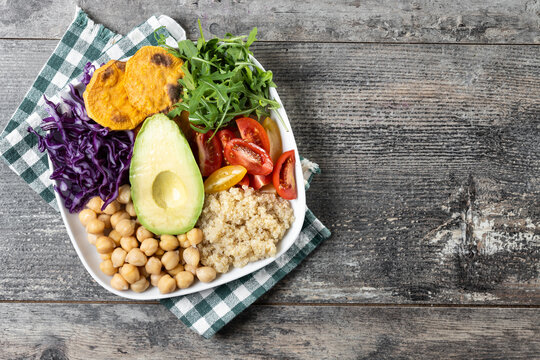 Healthy salad with avocado,lettuce,tomato and chickpeas on wooden table. Top view. Copy space