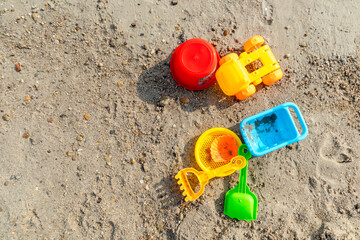 Set of plastic beach toys on sand on a sunny day. Top view.