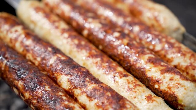 Grilled lula kebab on skewer on grill, close-up. Delicious homemade sausages