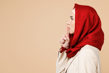 Young Arabian Asian Muslim woman wearing red abaya hijab suit clothes say hush be quiet with finger...