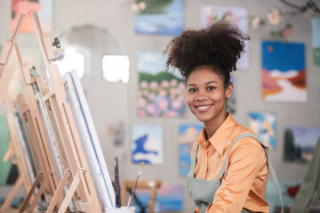 A young black artist paints acrylic paints on canvas with determination in her painting studio