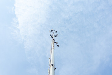 Obraz premium Spotlight pole with clouds and blue sky in background