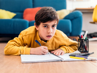 Naklejka premium A boy in a yellow sweatshirt looking frustrated about his homework.
