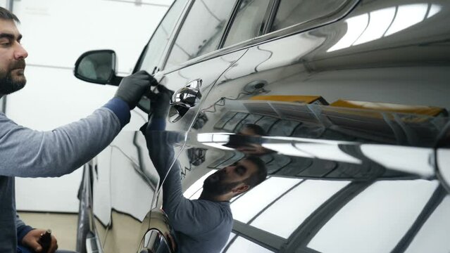 Staff wear Chemical protective clothing at work. Automobile industry. Car wash and coating business with ceramic coating.Spraying the varnish to the car. Concept of: Car protective, Service, Shine.	
