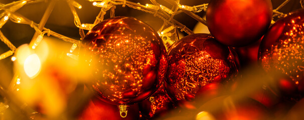 Banner red glowing Christmas balls garlands close-up. Holidays decoration and festive xmas concept...
