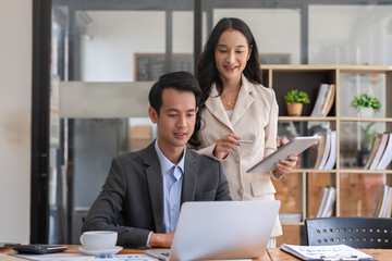 A young businessman and a female Asian accountant are discussing financial accounting and business planning together in the office.