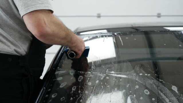 Applying tinting foil on a car window	
