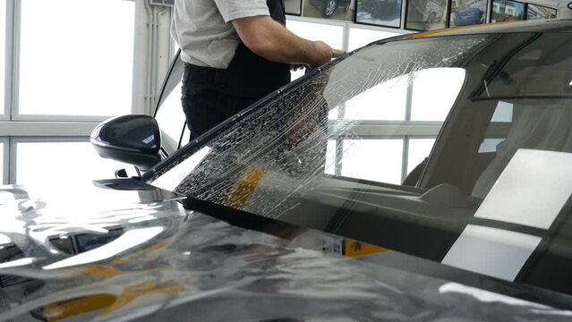 Applying tinting foil on a car window	
