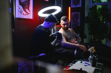 tattoo artist demonstrates the process of getting black tattoo with paint. Master works in black...