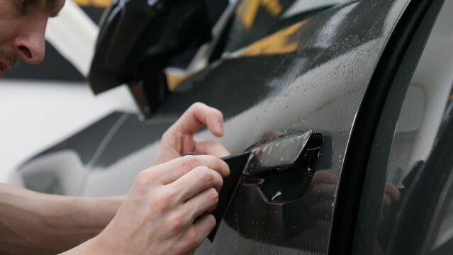 Close up of paint protection film installation on front bumper of modern luxury car. PPF is polyurethane film applied to car surface to protect the paint from stone chips, bug splatter, and abrasion.