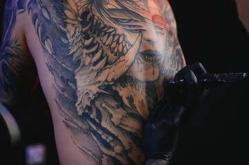 Tattoo artist man with black gloves draws a knight tattoo on the guy's back in the studio. Tattoo...