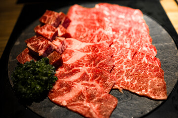 meticulously cut and well-arranged beef with premium marbling alongside fresh green herbs