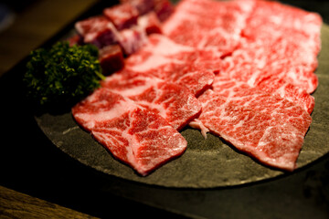 meticulously cut and well-arranged beef with premium marbling alongside fresh green herbs