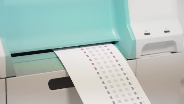 A printer is printing a white sheet of paper with a grid pattern on it