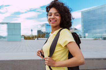 Young african happy smiling multiethnic female student with curly hair, wears yellow top and...