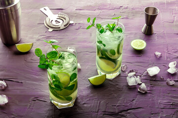 Mojito cocktail, two glasses. Summer cold drink with lime, fresh mint, and ice. Cool beverage on a...