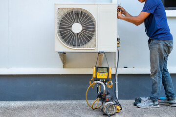 Male technician installing outdoor unit of air conditioner  to cool the household in the summer....