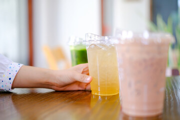 Woman hand hold plastic cup a lot of sweet or coffee on the wooden table background in cafe restaurant, celebrate,party, meeting