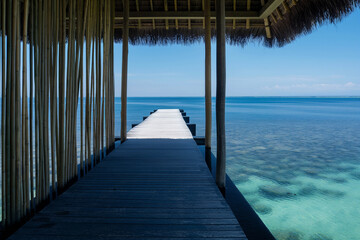 Beautiful beach with bamboo houses on the water against a blue sky background