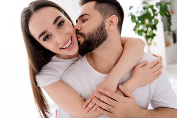 Photo of adorable charming boyfriend girlfriend sleepwear kissing hugging indoors home bedroom