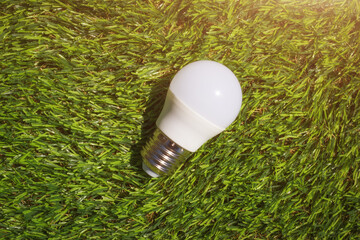 The modern led lamp on the green grass background. Concept of energy economy and environmental friendly household technologies. - 806905797